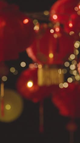 Vertical-Video-Of-Hands-Exchanging-Card-Celebrating-Chinese-New-Year-With-Chinese-Lanterns-Hung-In-Background